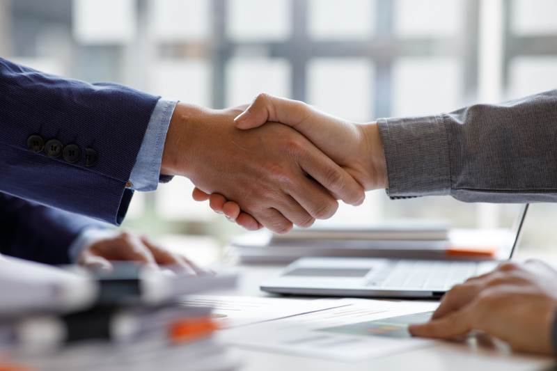 地域の人々とスタッフが信頼感のある握手をしている様子